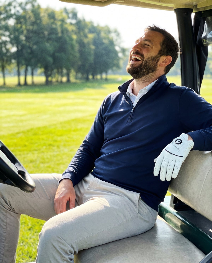 Man in a navy quarter zip on a golf course