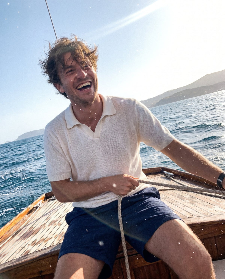 Man in a white knit polo on a sailing boat